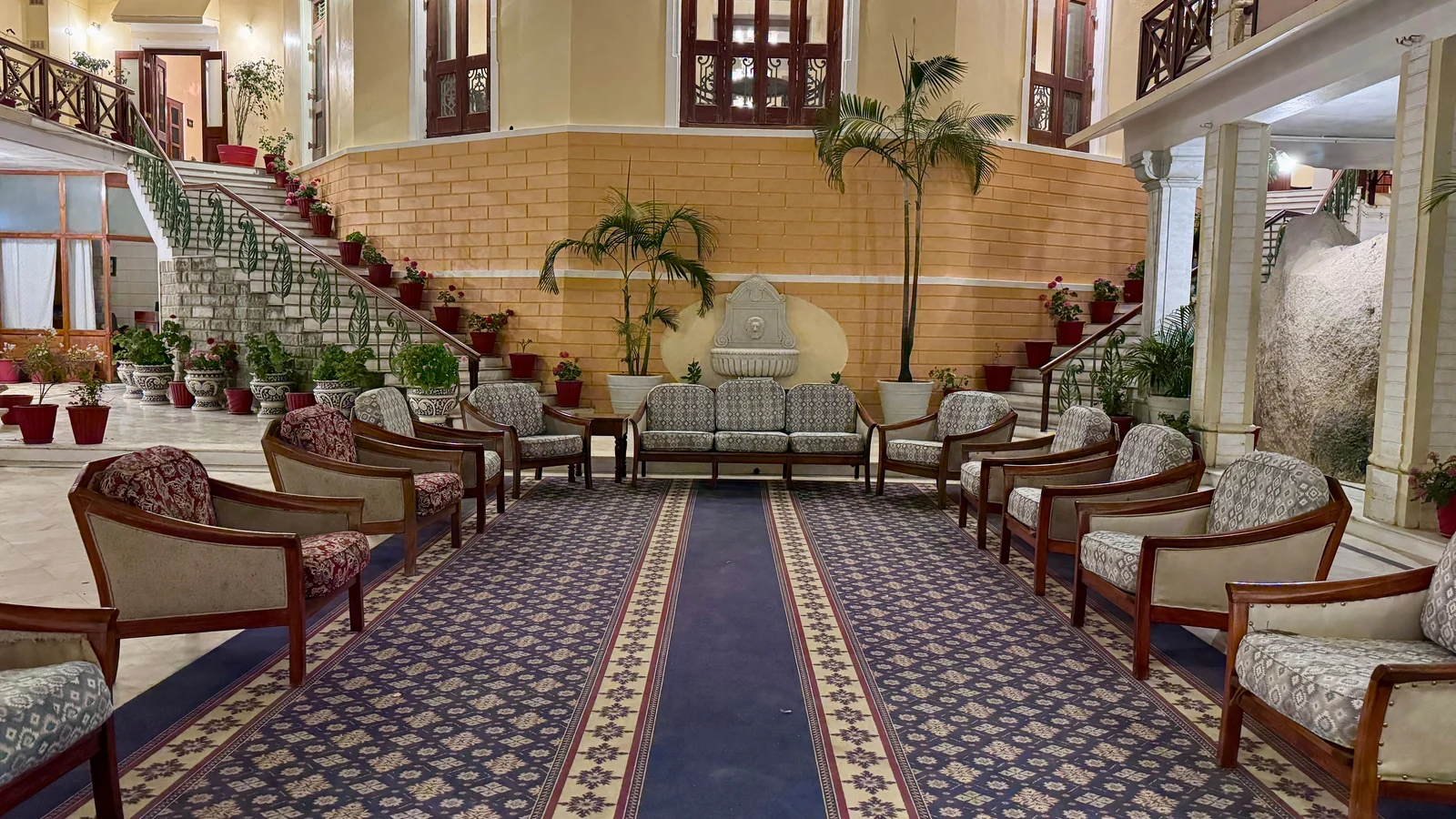 Spacious interior with patterned seating, a central carpet and staircases.